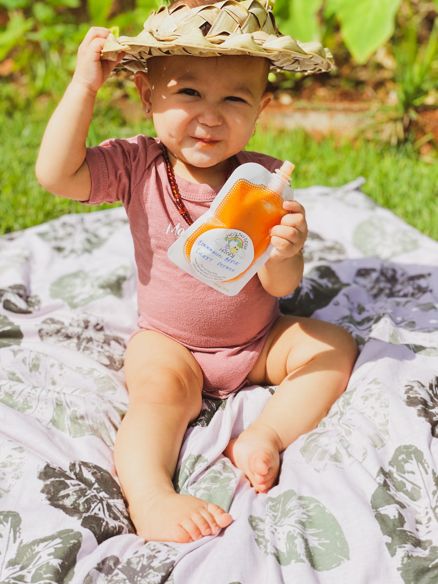 the keiki dept baby eating healthy baby hawaii food. she is sitting on a kalo stamp kapa moe blanket 